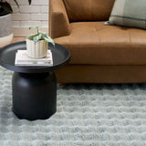 Living room with a brown sofa, black side table, and gray rug.